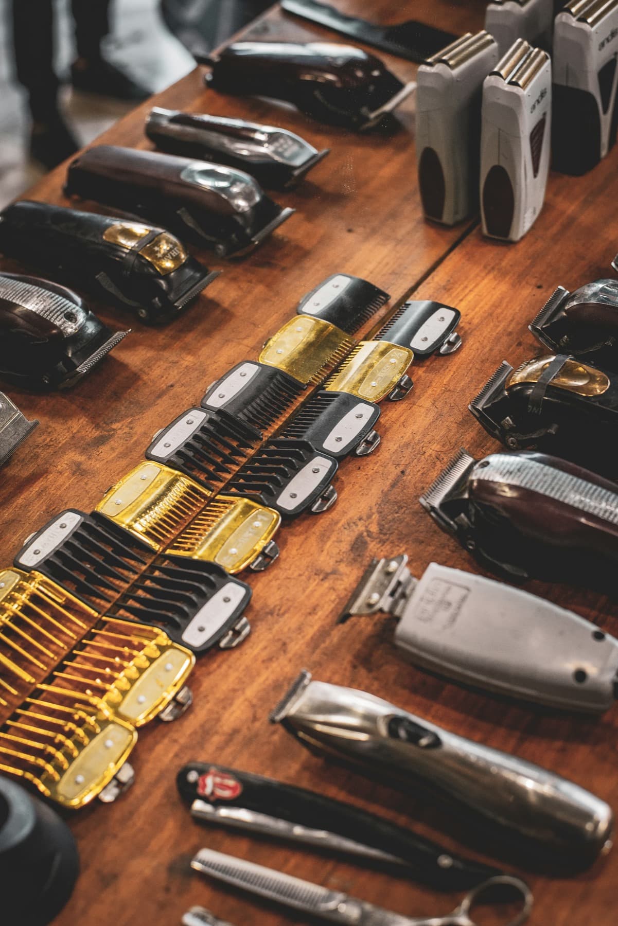 Barber clippers and guard combs laid out on a warm wooden counter